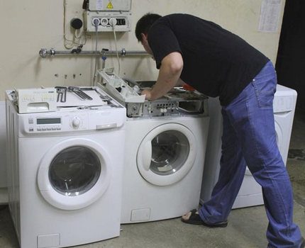 Meistras apžiūri skalbimo mašinas