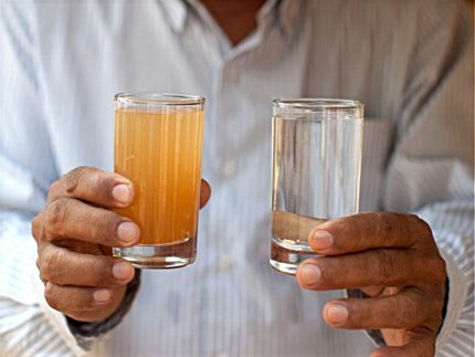 Man holds glasses with dirty and clean water.